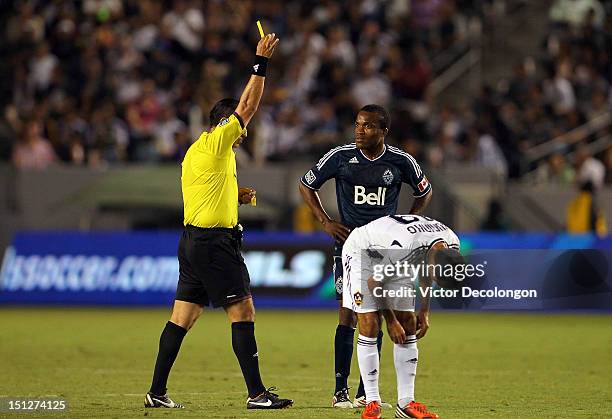 Dane Richards of the Vancouver Whitecaps looks at referee Baldomero Toledo as Toledo books Richards with a yellow card during the MLS match at The...