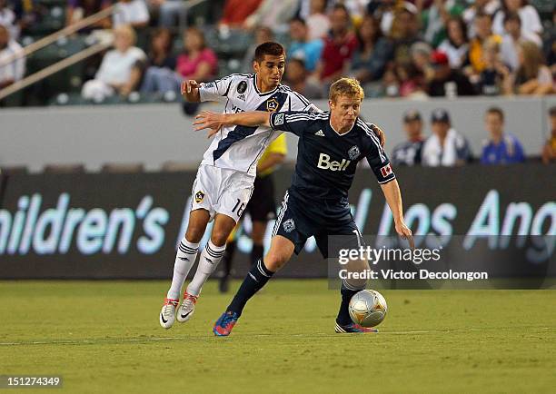 Barry Robson of the Vancouver Whitecaps holds off a challenge from Hector Jimenez of the Los Angeles Galaxy in the first half during the MLS match at...