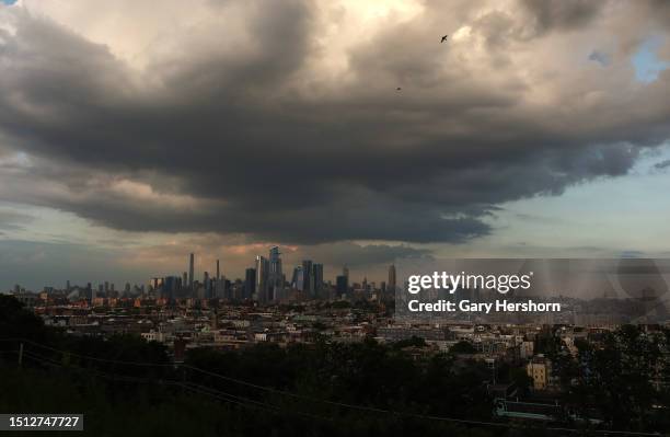 Storm cloud passes over the midtown Manhattan skyline, Hudson Yards, and the Empire State Building as the sun sets in New York City on July 3 as seen...