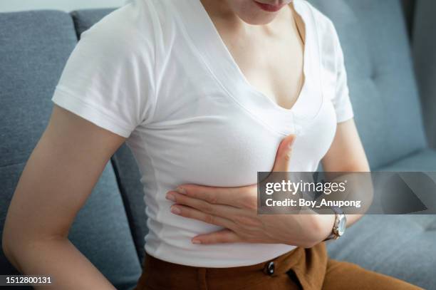 cropped shot of woman touching her breast for checking cancer awareness. women of all ages are encouraged to perform breast-self exams at least once a month. - pechos mujer fotografías e imágenes de stock