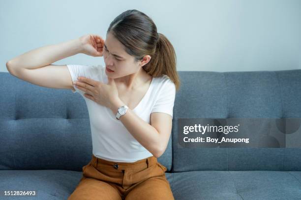 asian woman touching her armpit for checking swollen axillary lymph nodes under her armpit. - oksel stockfoto's en -beelden