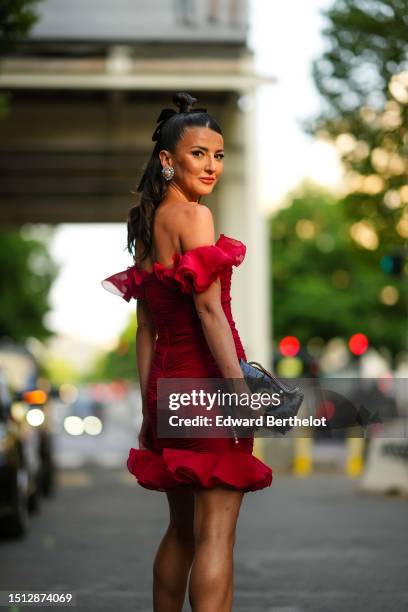 Alexandra Pereira wears rhinestones and diamonds large earrings, a red ruffled shoulder-off / short sleeves / tube short dress from Giambattista...