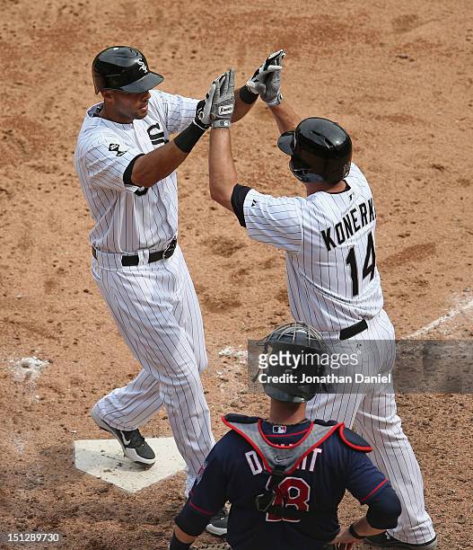 Alex Rios of the Chicago White Sox is greeted by teammate Paul Konerko after hitting a two-run home run in the 6th inning as Ryan Doumit of the...