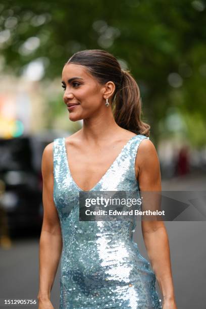 Camila Coelho wears gold with large silver pearls earrings, a pale blue embroidered sequined V-neck / tank-top long dress, silver rings, outside...