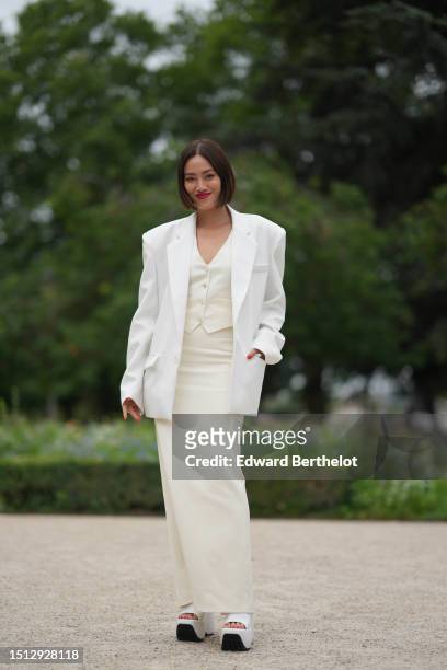 Tiffany Hsu wears a white latte buttoned gilet, a matching white latte long tube skirt, a white oversized blazer jacket, white shiny leather with...