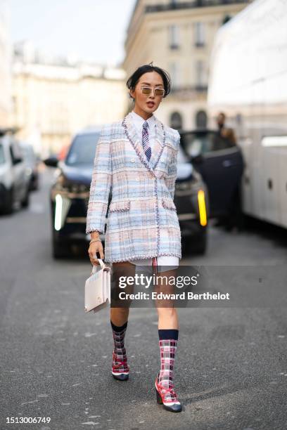 Chriselle Lim wears white sunglasses, a pale baby blue shirt short dress, a navy blue / red / white checkered print pattern tie, a pale blue / beige...