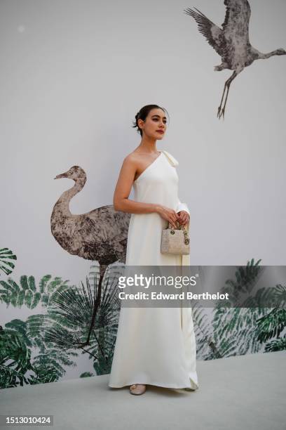 Kimberley Anne Woltemas wears a white latte asymmetric shoulder long dress, a beige with embroidered rhinestones Lady D-Light handbag from Dior,...