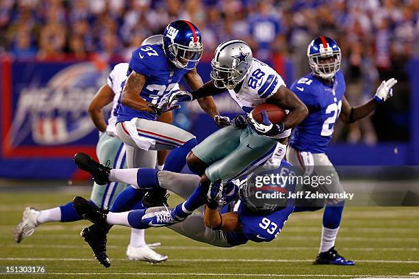 Wide receiver Dez Bryant of the Dallas Cowboys gets tackled by linebacker Chase Blackburn and defensive back Michael Coe of the New York Giants...