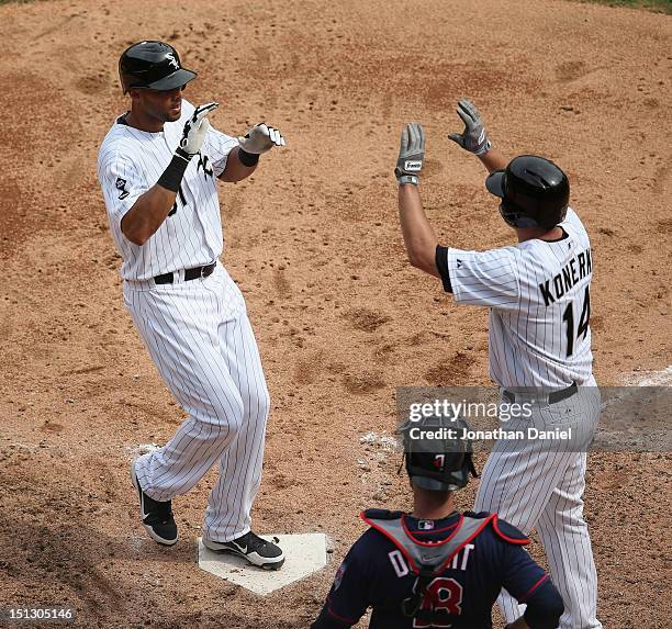 Alex Rios of the Chicago White Sox is greeted by teammate Paul Konerko after hitting a two-run home run in the 6th inning as Ryan Doumit of the...