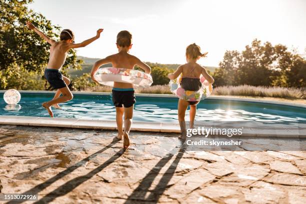 verspielte geschwister, die sich am sommertag am pool vergnügen. - schwimmbad stock-fotos und bilder