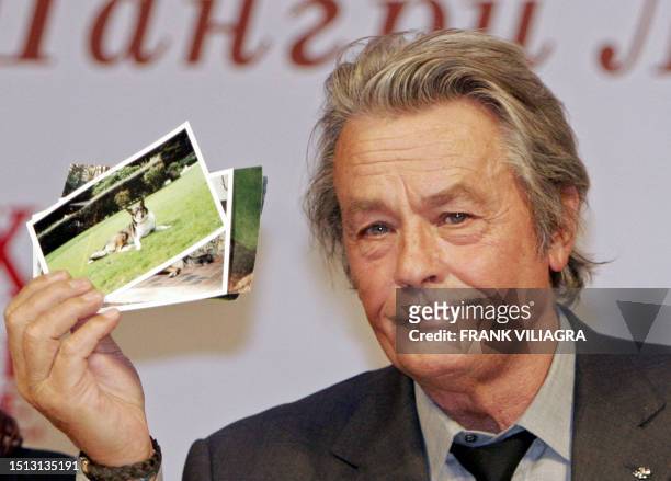 French actor Alain Delon shows pictures of two dogs that he was given as a gift by Alexander Lebed, a Russian general and political who died in April...