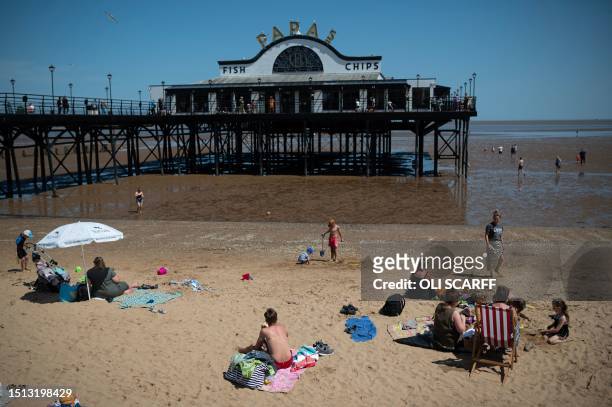 Members of the public relax on the beach in hot weather in Cleethorpes, north east England on July 7, 2023