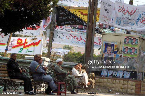 Egyptians sit near electoral campaign banners in Fayyum, 130 kms south of Cairo, on November 26, 2011 ahead of a three-round parliamentary election....