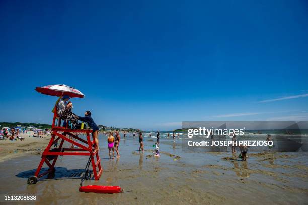 Lifeguards prepare to move back their chair as the tide comes in at Good Harbor Beach in Gloucester, Massachusetts on July 7, 2023.