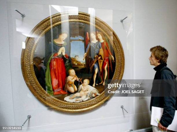 A person looks at the painting called "Adoration de l'Enfant, Saint-Jean et les anges musiciens" of Italian painter Piero di Cosimo as he visits the...