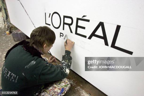 Worker at the Werner Werbung cinema billboard painting workshop paints the logo of French cosmetics giant L'Oreal on a billboard at a Berlin atelier...