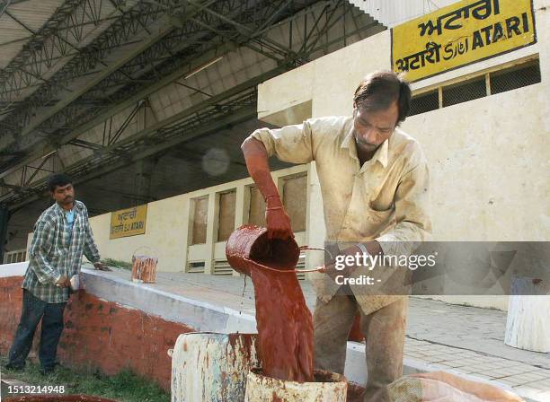 Indian workers apply a fresh coat of paint to the platform of the Atari railway station, 06 May 2003 in Punjab state, the last stop in India on the...