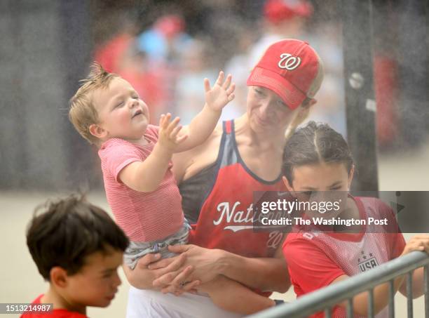 Christine Barrett of Reston cools down with her one year old son Grant as the Cincinnati Reds and Washington Nationals play at Nationals Park on July...