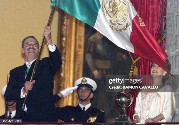 Mexican President Vicente Fox waves the national flag, accompanied by his wife Marta Sahagun, during ceremonies celebrating 180 years of Mexican...