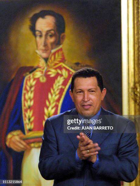 Hugo Chavez, president of Venezuela, stands in front of a painting of Simon Bolivar, as he applauds during a meeting in the Presidential Palace in...