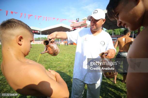 An official helps wrestler boys get their bodies oiled ahead of the second day of 662nd Kirkpinar Oil Wrestling Festival in Edirne, Turkiye on July...
