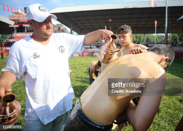 An official helps wrestler boys get their bodies oiled ahead of the second day of 662nd Kirkpinar Oil Wrestling Festival in Edirne, Turkiye on July...