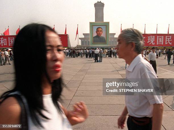 Beijingers walk through Tiananmen Square as National Day preparations are under way throughout the city, including the annual hanging of a picture of...