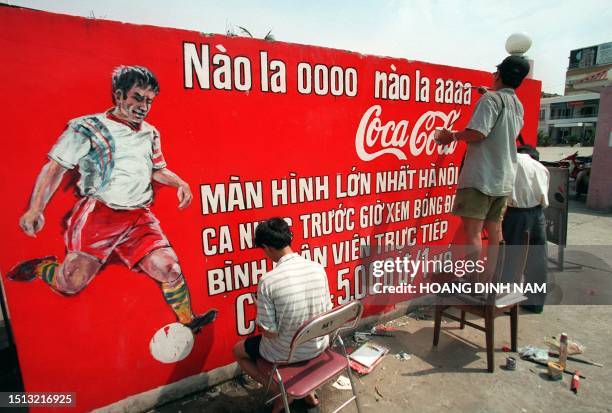 Workers paint an advertising 09 June to be displayed during a public viewing of the World Cup on a 300-inch screen to be held at Hanoi's Exhibition...