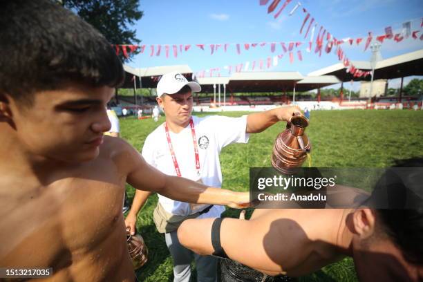 An official helps wrestler boys get their bodies oiled ahead of the second day of 662nd Kirkpinar Oil Wrestling Festival in Edirne, Turkiye on July...