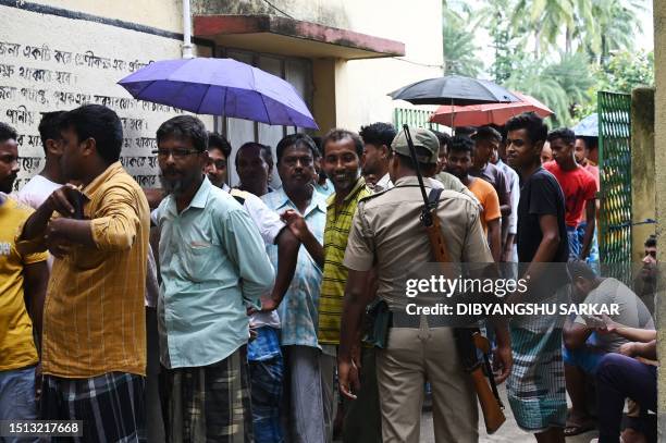 Police officer stands guard as people queue at a polling station to cast their vote in West Bengal's 'Panchayat' or local elections, on the outskirts...