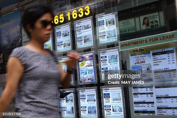 Woman walks past a property agent in Hong Kong on July 8, 2023.