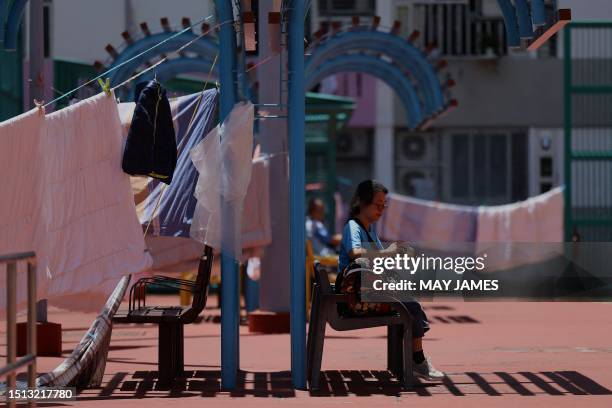 Woman eats at a playground next to residential buildings on July 8, 2023.