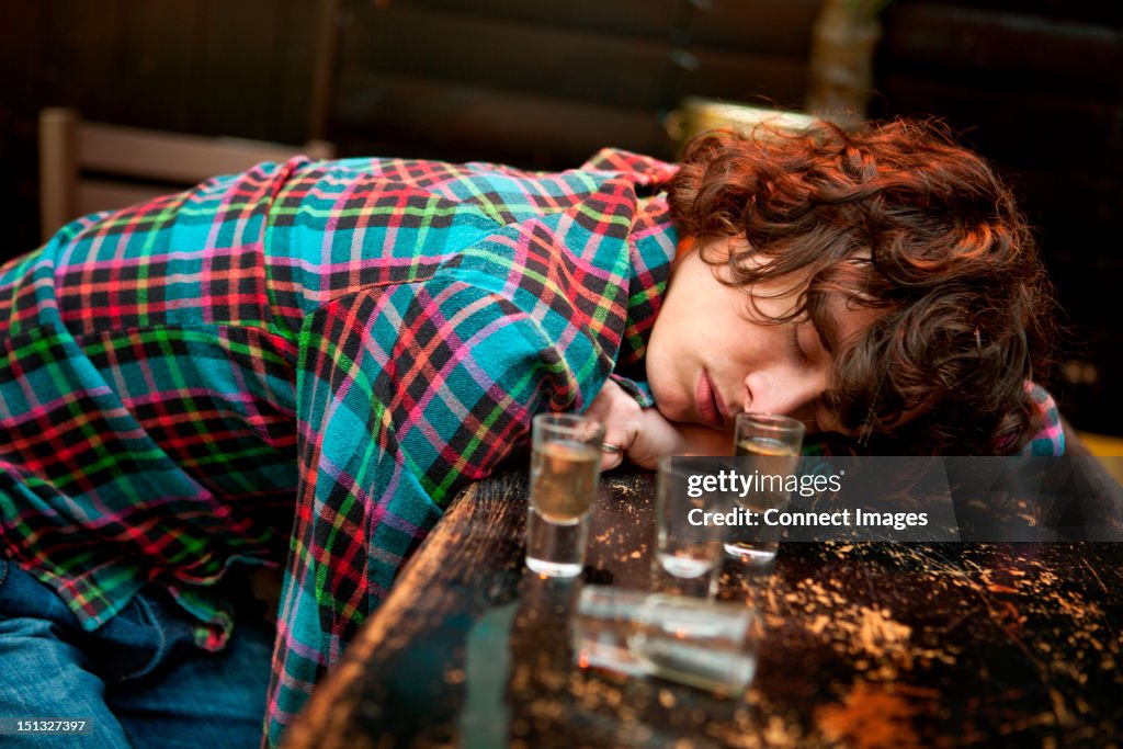 Drunk man slumped on bar asleep