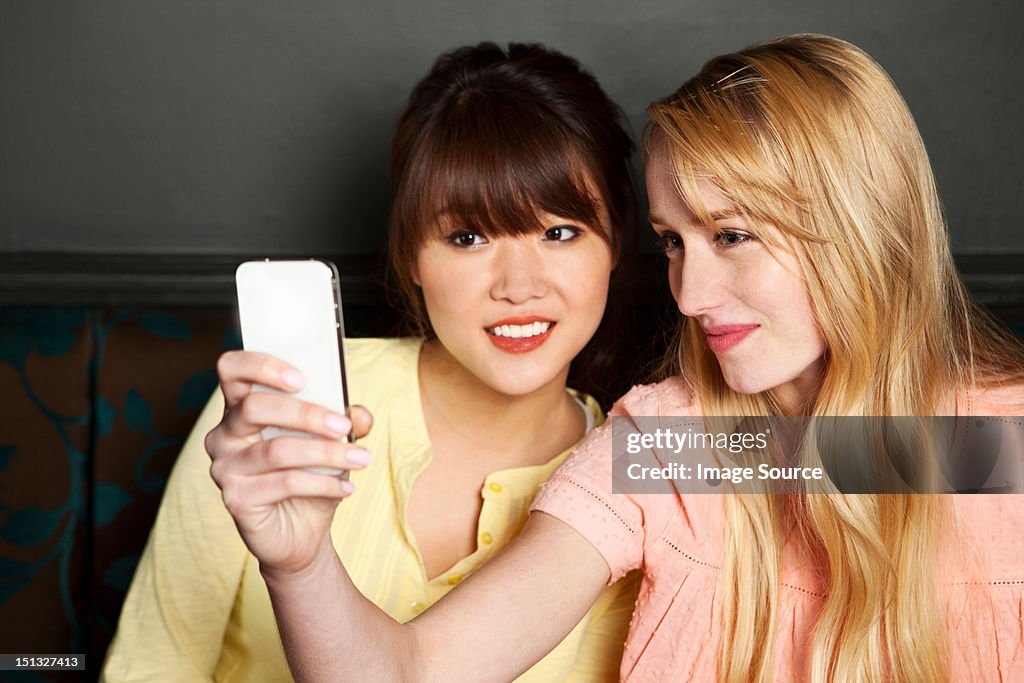 Female friends photographing themselves on smartphone