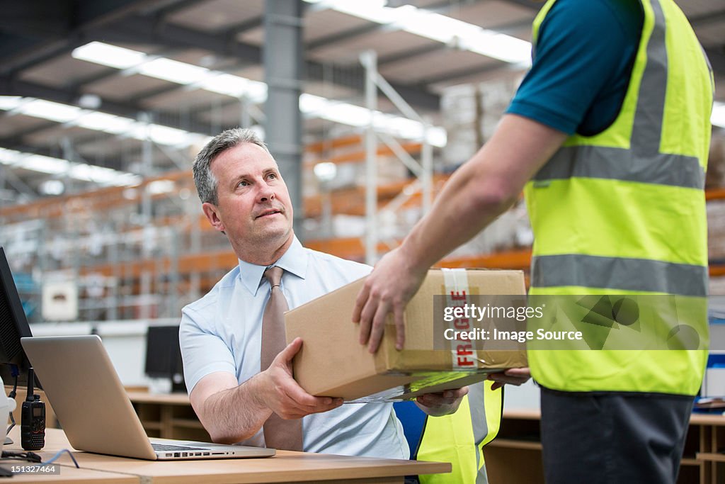 Man delivering cardboard box to another man