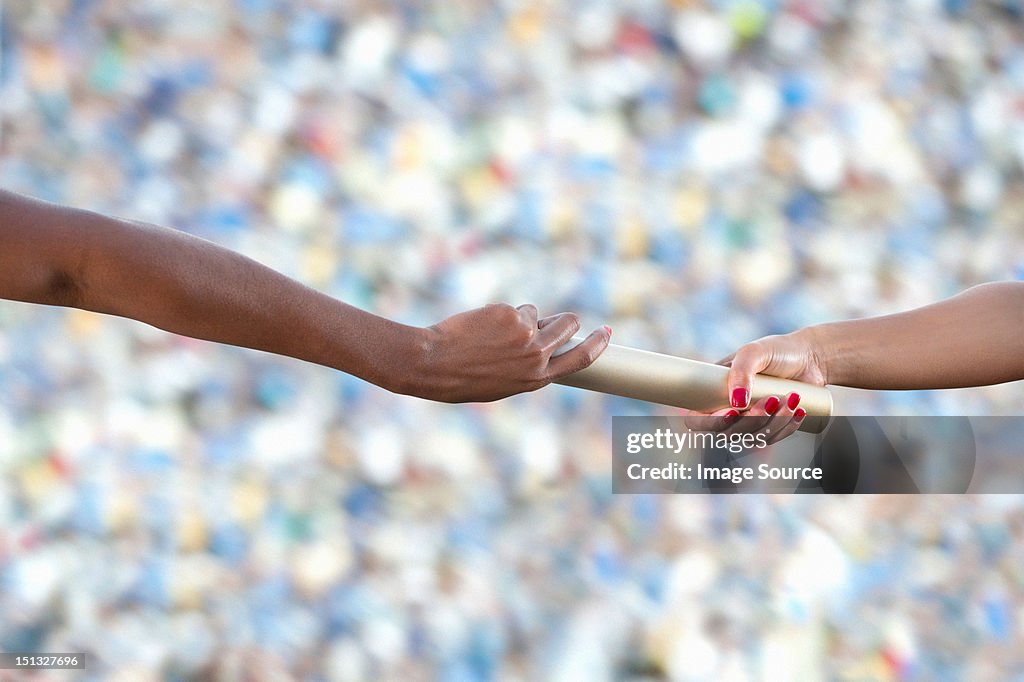 Relay athletes passing a baton, close up