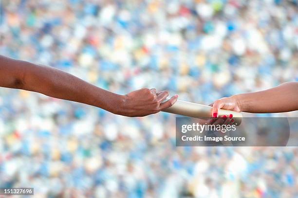 relay athletes passing a baton, close up - relais athlétisme mains photos et images de collection