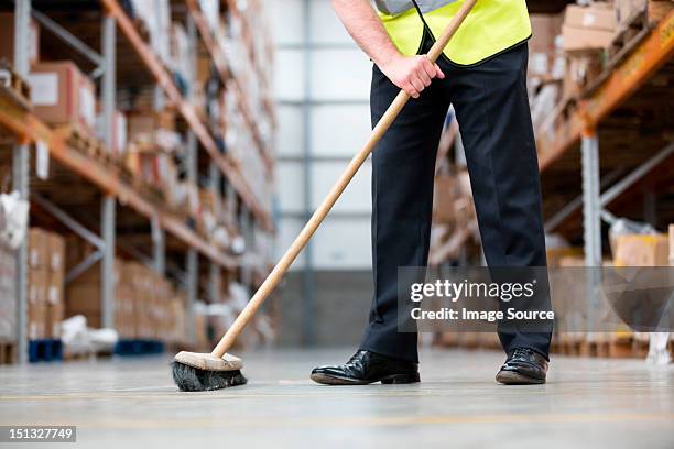 man sweeping warehouse floor with broom - 掃地 個照片及圖片檔