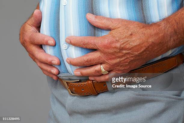 overweight senior man touching stomach - dicker bauch stock-fotos und bilder