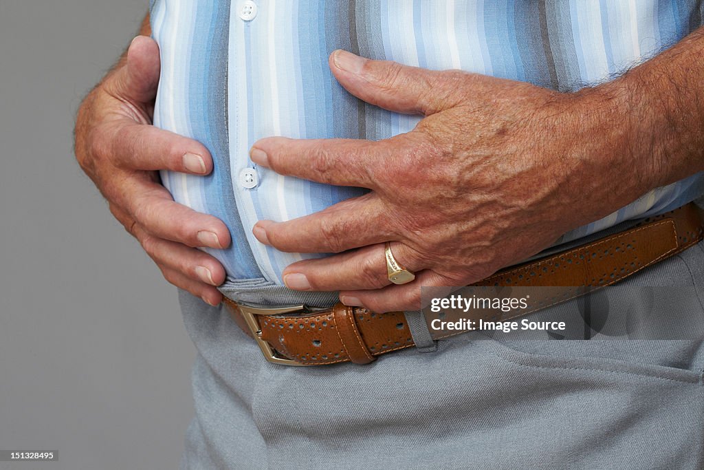 Overweight senior man touching stomach