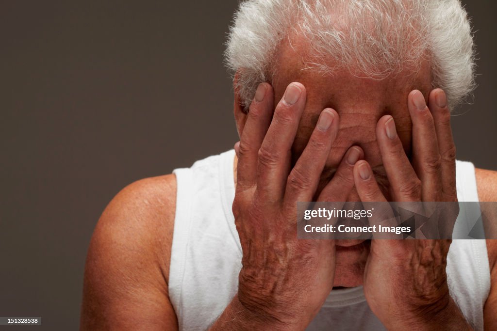 Senior man with head in hands