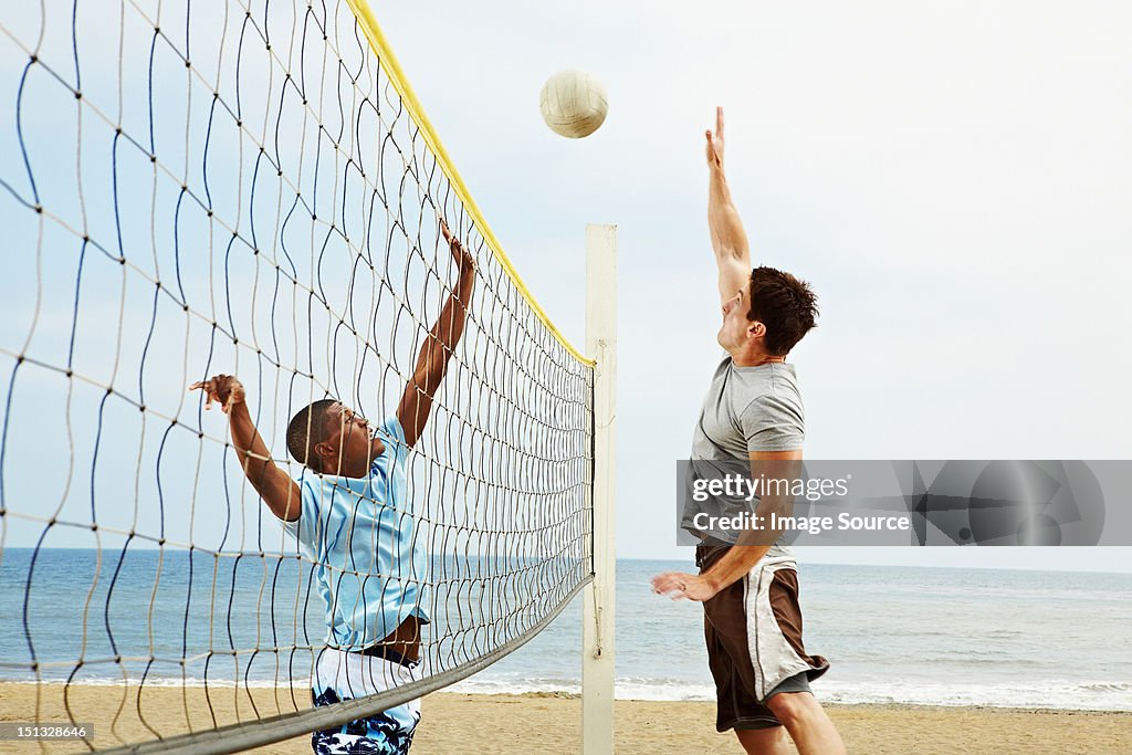 Two young men playing beach volleyball