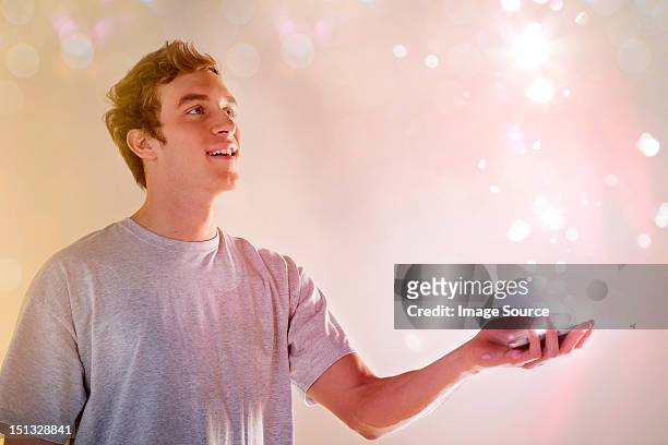 young man looking at lights coming from cellphone - smartphone hologram stock-fotos und bilder