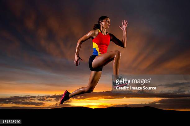athlete in mid air against sunset - woman long jump stock-fotos und bilder