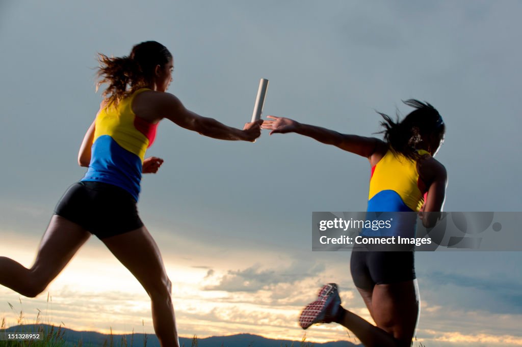 Female relay racers passing baton