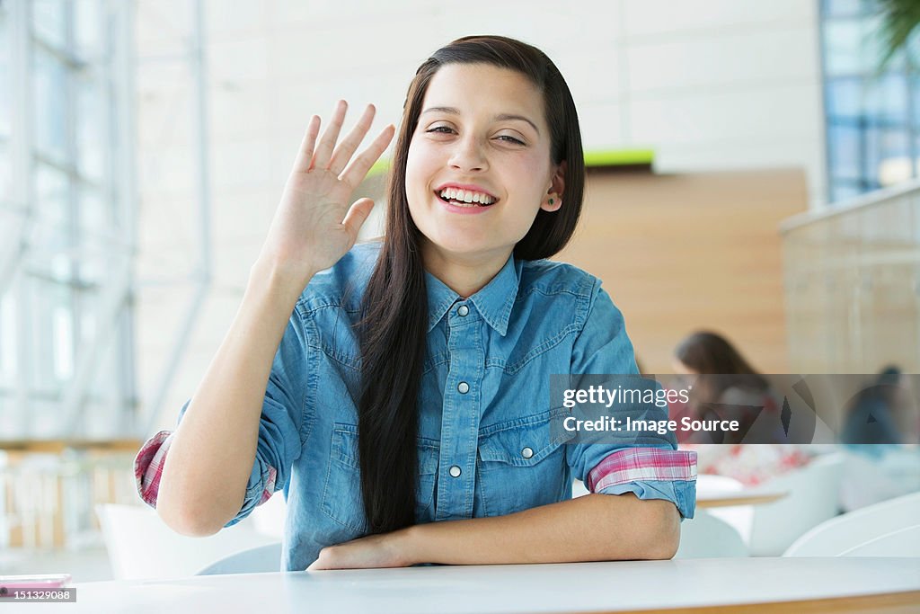 Young woman waving at camera