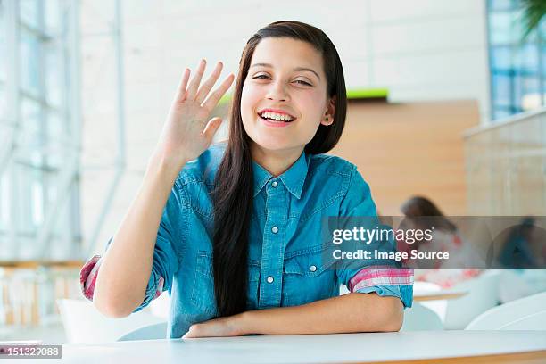 young woman waving at camera - hand waving stock pictures, royalty-free photos & images