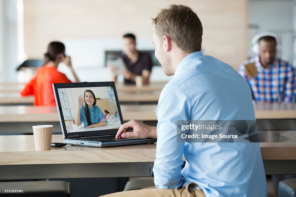 Young man using laptop to have video call with girlfriend