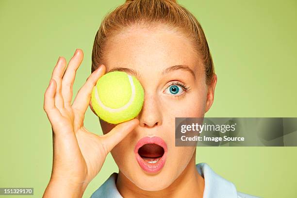 young woman holding tennis ball over her eye - focus on sport 2012 stock pictures, royalty-free photos & images