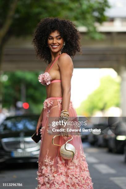 Guest wears gold rhinestones pendant earrings, a pale orange embroidered ruffled flower bra top, a matching pale orange tulle with embroidered...